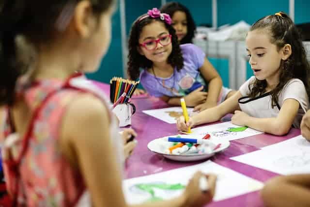 Imagem de uma artista pintando com as crianças na Fenearte 2019