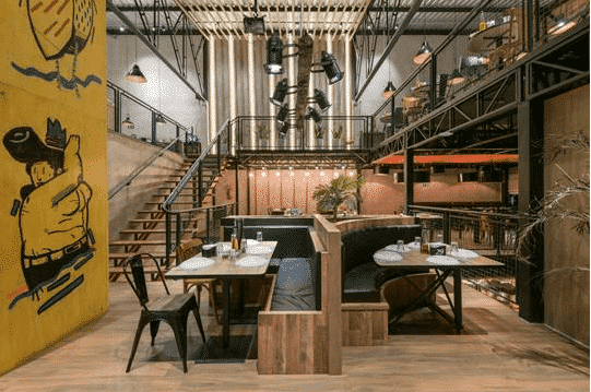 Restaurante com desenhos nas paredes, refletores, poltronas em paletes