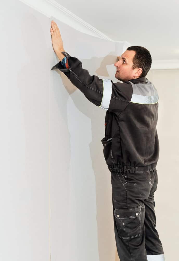 worker install wallpaper wall home restoration concept man glues wallpaper wall vertical frame - Como colocar papel de parede: confira 5 passos simples que vão ajudar nesta tarefa