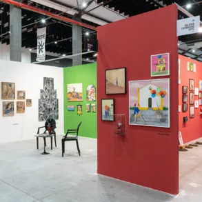 Estandes de galerias em feira de arte, com paredes coloridas em branco, verde e vermelho exibindo quadros, esculturas e objetos diversos sob estrutura industrial de teto. Fotos Danilo Galvão