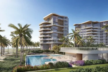 Renderização de dois edifícios residenciais com varandas curvas e fachada bege, cercados por palmeiras, jardins e piscina à beira-mar.