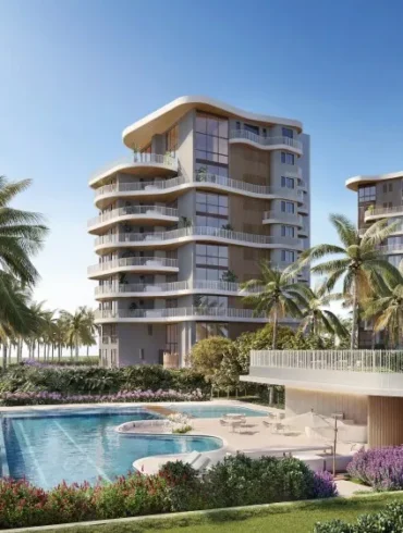 Renderização de dois edifícios residenciais com varandas curvas e fachada bege, cercados por palmeiras, jardins e piscina à beira-mar.
